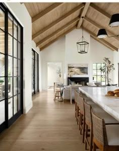 an open kitchen and dining room with wood floors, white walls, and vaulted ceiling