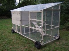 a small white chicken coop sitting in the grass