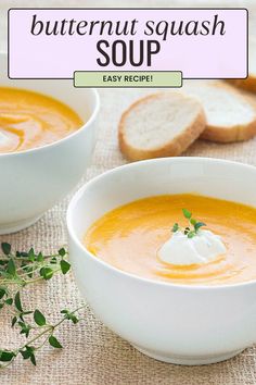 two bowls of butternut squash soup on a table with bread and sprigs