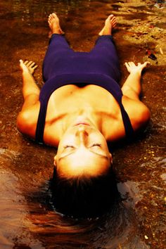 a woman laying in the water with her hands up above her head and an inspirational quote below