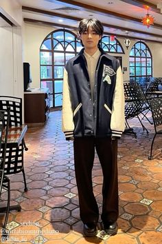 a young man standing in front of a table with chairs and tables behind him on the floor