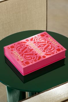 a pink box sitting on top of a table next to a white chair and green table