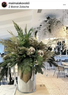 a vase filled with lots of greenery on top of a table