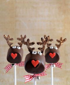 three chocolate reindeer lollipops with hearts on them sitting on top of each other