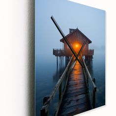 a wooden pier with a light on it in the middle of water at night time