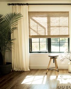 a living room with wooden floors and large windows covered in natural shades of bamboo blinds