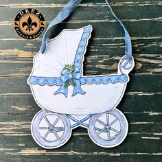 a paper cut out of a baby's carriage hanging on a wooden table with a blue ribbon