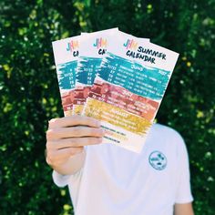 a man holding up two tickets for the summer calendar