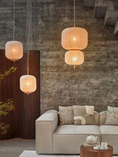 a living room with two couches and three lamps hanging from it's ceiling