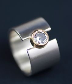 A minimalist, modern, timeless design with just a little extra edge, this lunar beauty is given that extra something with a brilliant, sparkly, 6mm moissanite. This sleek, bold design will turn heads yet looks great with everything. The brushed finished band accents the richness of the gold setting, which can be emphasized further by the optional 2mm 14K gold band. Wide Band Engagement Ring, Modern Wedding Rings, Modern Wedding Band, Alternative Wedding Bands, Wide Wedding Bands, Modern Engagement Rings, Lunar Eclipse, Alternative Engagement Rings, Wide Band Rings