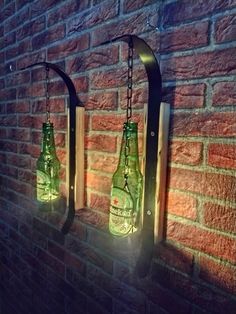 three green bottles are hanging on a brick wall, one is lit up and the other is empty