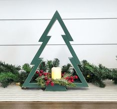 a candle is lit in front of a christmas tree with greenery and pine cones