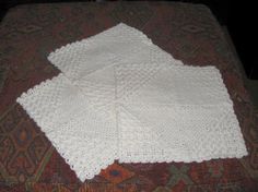 two white crocheted napkins sitting on top of a rug