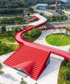 an aerial view of a red curved walkway in the middle of a green area with trees and buildings