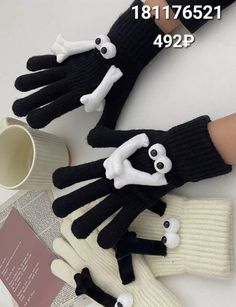 three black and white gloves with skulls on them, one is wearing a skull glove