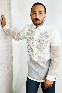 a man standing next to a wall wearing a white shirt