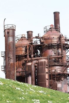 an old factory building sitting on top of a green hill