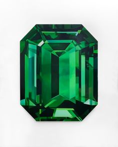 an emerald colored diamond is displayed on a white surface with black and green trimmings