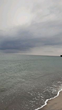 a boat is out on the water in front of an overcast day at the beach