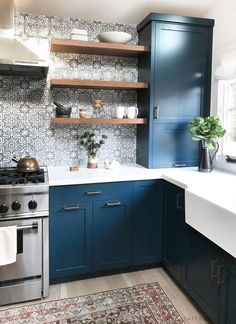 a kitchen with blue cabinets and an area rug in front of the stove top oven