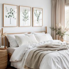 a bed with white sheets and pillows in a bedroom next to two framed pictures on the wall