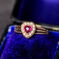 A gorgeous little antique heart-shaped ring from the Edwardian period!  This high quality piece dates from around 1910 and is in solid 14 carat gold. Its heart-shaped head is set with a beautiful lab-grown heart-shaped ruby which is a wonderful shade of pink-red. It's surrounded by little seed pearls in a long claw channel setting, and the head's underbezel is an extremely charming deep gallery, allowing light to flood in from beneath the ruby. Its shoulders are fabulous, gently tapering triple forks, whose ribbing continues all the way around the band - my favourite aspect of this piece.  It's marked '585' to warrant the gold content at solid 14 carat and is a very wearable size 6 resizable. It measures just 9 mm across the head and weighs in at 1.5 grams. It's in lovely condition through Victorian Heart-shaped Anniversary Rings, Antique Heart-shaped Rings For Formal Occasions, Antique Heart-shaped Promise Ring, Heirloom Heart Ring For Valentine's Day, Vintage Yellow Gold Heart Ring, Antique Heart Shaped Wedding Rings, Vintage Yellow Gold Heart Cut Ring, Safe Deposit Box, Heart Shaped Ring