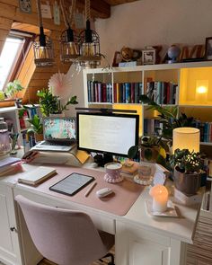 a desk with a computer, laptop and books on it