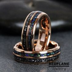 two wedding rings with blue and green glitters on them, sitting next to each other