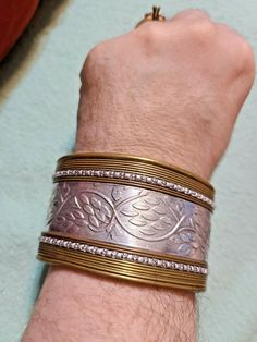 a man's arm with two different bracelets on it, one is gold and the other is silver