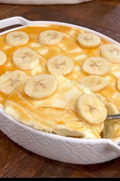 banana pudding in a white casserole dish on a wooden table with a serving utensil