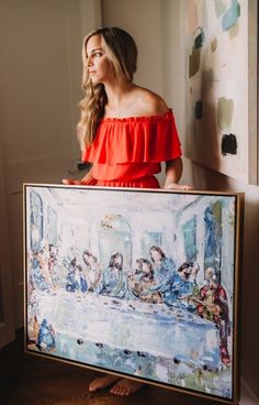 a woman in an orange dress holding a large painting