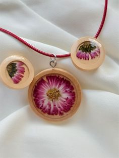 two necklaces with pink flowers on them sitting on a white cloth covered tablecloth