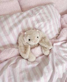 a stuffed animal sitting on top of a pink blanket