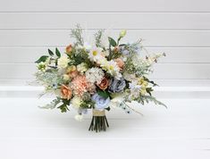 a bouquet of flowers sitting on top of a white table next to a wooden wall