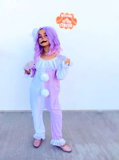 a person with purple hair wearing a costume and holding a pom - pom