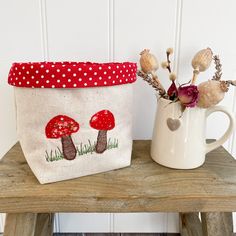 two small bags sitting next to each other on a wooden table near a vase with flowers in it