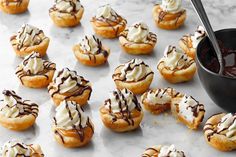 small pastries with chocolate drizzled on them and a bowl of sauce