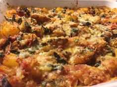 a casserole dish with meat, cheese and spinach toppings on top