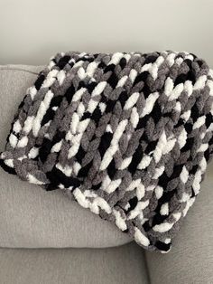 a black and white blanket sitting on top of a couch next to a gray chair