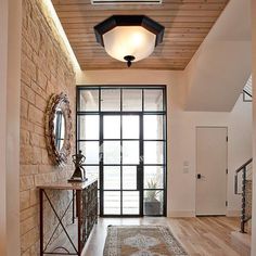 an entry way with a rug, mirror and light fixture