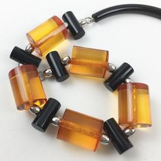 A fabulous piece of jewelry art by Judith Hendler. This necklace is from the 1980s. It has the iconic acrylic or Lucite neck tube ring, and from it are elegant geometric large beads Acri-gems in assorted colors of transparent orange and true licorice black. A rare and truly spectacular piece. Measurements: necklace circumference is 19.94 in long (51 cm) - the orange bead is 1.25 in long (3.2 cm) x 1 in diameter (2.5 cm).  Please see the measurements noted above in the description for the best ap Modern Round Lucite Jewelry, Modern Glass Necklaces For Formal Occasions, Modern Glass Necklaces For Formal Events, Vintage Amber Resin Jewelry, Retro Lucite Jewelry As Gift, Retro Lucite Jewelry Gift, Retro Lucite Jewelry Perfect As A Gift, Unique Orange Glass Jewelry, Elegant Amber Resin Jewelry