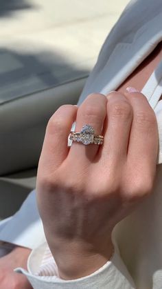 a woman's hand with a diamond ring on her left finger, sitting in a car