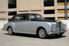 an old silver car parked in front of a building