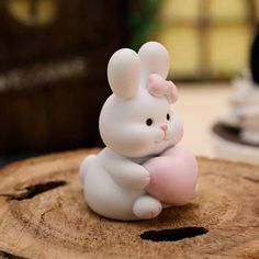 a small white rabbit figurine sitting on top of a wooden stump