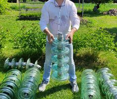 a man standing in the grass with many green vases