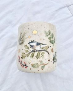 a white ring with a bird painted on the side and pine branches in the middle