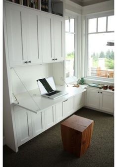 a laptop computer sitting on top of a desk next to a window in a room