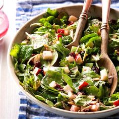 a salad in a bowl with two wooden spoons