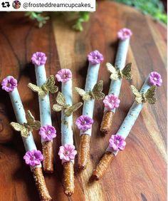 five small candles with flowers on them sitting on a wooden table next to some plants