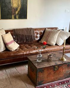 a brown leather couch sitting next to a wooden trunk